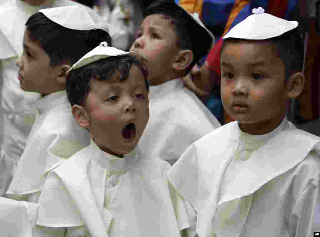 Seorang anak yang berpakaian seperti Paus menguap saat menunggu upacara kanonisasi di Vatikan terhadap Paus Yohanes Paulus II&nbsp;​dan Paus Yohanes ke-23.