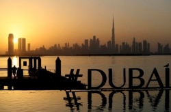 Seorang pria menikmati matahari terbenam dengan pemandangan cakrawala kota dan menara tertinggi di dunia, Burj Khalifa, di Dubai, Uni Emirat Arab, Jumat, 29 Januari 2021. (Foto: AP/Kamran Jebreili)