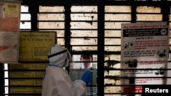 A medical worker gets ready to collect a sample from a man at a school turned into a center to conduct tests for the coronavirus disease (COVID-19), amidst its spread in New Delhi, India, June 22, 2020.