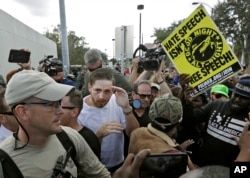 A supporter of white nationalist Richard Spencer, center in white shirt, tries to cover up as he clashes with the crowd after a speech by Spencer, Oct. 19, 2017, at the University of Florida in Gainesville.