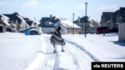 Un homme se rend à pied chez son ami dans un quartier sans électricité alors que la neige recouvre le quartier de BlackHawk à Pflugerville, au Texas, aux États-Unis, le 15 février 2021. 