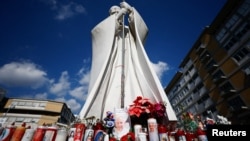 Decorated candles and flowers sit next to a statue of the late Pope John Paul II outside Rome's Gemelli Hospital, where Pope Francis is admitted for treatment of pneumonia, on Feb. 22, 2025.