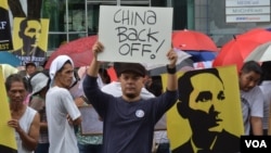 Manila artist and historian Carlos Celdran holds up a hand-written sign as demonstrators outside the Chinese consulate in Manila protest China's reclamation activity at Johnson South Reef, locally known as Mabini Reef, in the South China Sea, June 12, 201