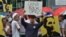 Manila artist and historian Carlos Celdran holds up a hand-written sign as demonstrators outside the Chinese consulate in Manila protest China's reclamation activity at Johnson South Reef, locally known as Mabini Reef, in the South China Sea, June 12, 201