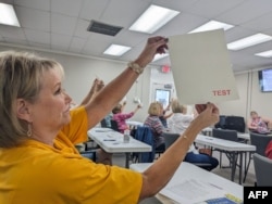 Lee County poll workers look for watermarks on the ballot during poll worker training in Leesburg, Georgia, Oct. 2, 2024.