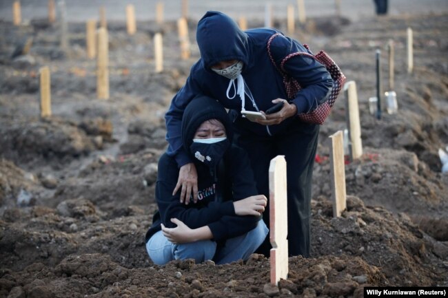 Seorang gadis berduka usai pemakaman ayahnya yang berusia 56 tahun yang meninggal karena COVID-19, di area pemakaman yang disediakan pemerintah untuk korban COVID-19, di Jakarta, 28 Juni 2021.(Foto: REUTERS/ Willy Kurniawan)