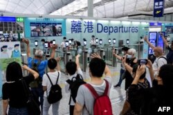 FILE - This picture taken on July 22, 2021, shows people (bottom) waving goodbye as passengers make their way through the departure gates of Hong Kong's International Airport. (Photo by ISAAC LAWRENCE / AFP)