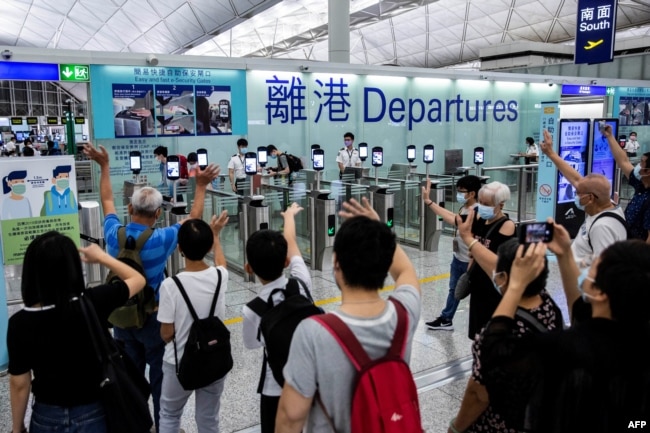 FILE - This picture taken on July 22, 2021, shows people (bottom) waving goodbye as passengers make their way through the departure gates of Hong Kong's International Airport. (Photo by ISAAC LAWRENCE / AFP)