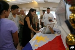 Philippine Senator Sonny Angara, second from left, and his wife, Elvira, pay their respects to Philippine Marine Pfc. Marvin Gomez, killed in the fighting with Muslim militants in Marawi City in southern Philippines, June 13, 2017 in Taguig city, east of Manila, Philippines.