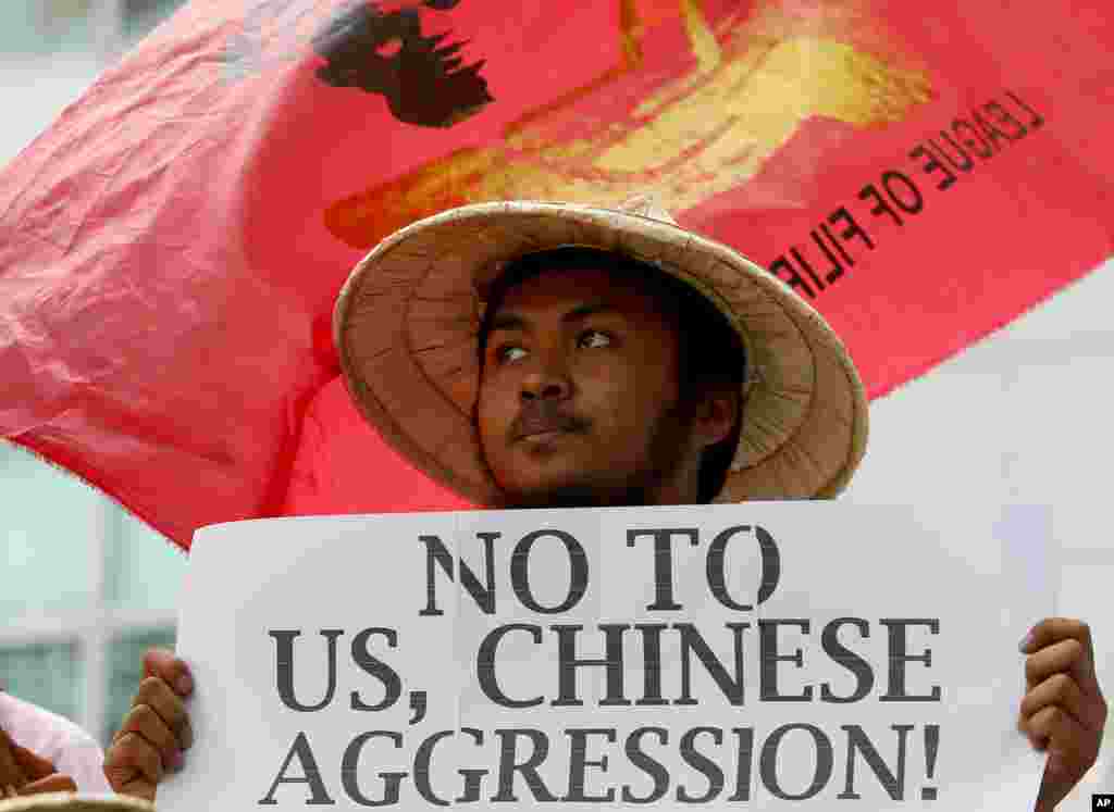 Seorang demonstran memegang poster saat pawai untuk rasa dekat Konsulat China di distrik finansial kota Makati, Filipina, mengecam pengerahan misil China di pulau-pulau yang disengketakan di Laut Cina Selatan.