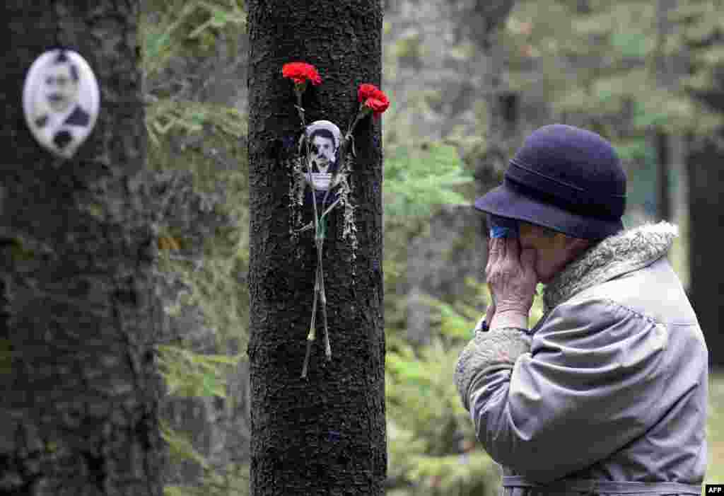Seorang perempuan menangis melihat foto para korban pembunuhan semasa diktator Uni Soviet Joseph Stalin, di lokasi di mana para korban dikuburkan di Saint-Petersburg, Rusia.