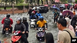 Motorists cross a flooded street after heavy monsoon rains in downtown Kota Bharu, Kelantan, Malaysia, on Nov. 29, 2024.