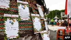 Kartu Natal bertuliskan "Tahun 2020 Segel Gereja Kami Dibuka" dipajang di antara pesan-pesan lainnya dalam kebaktian Natal oleh umat Kristiani di depan Istana Presidenan, di Jakarta, 25 Desember 2019. (Foto: AFP)