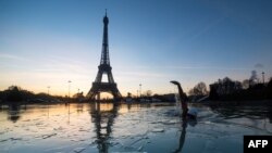 Seorang pria berenang di kolam air mancur Trocadero di depan Menara Eiffel di Paris (6/1). (AFP/Olivier Morin)