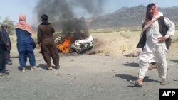 Pakistani local residents gather around a burning vehicle hit by a U.S. drone strike, May 21, 2016. Afghan Taliban Mullah Akhtar Mansoor was the target of the drone near Dalbandin, Baluchistan, Pakistan.