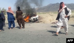 FILE - Local residents gather around a burning vehicle hit by a U.S. drone strike targeting a Taliban leader, near Dalbandin, Baluchistan, Pakistan, May 21, 2016. Islamabad has called on Washington to respect its sovereignty and refrain from conducting similar strikes.
