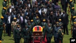 The casket of former Zimbabwean president Robert Mugabe, covered by the national flag and followed by family and dignitaries, arrives for a state funeral at the National Sports Stadium, in the capital Harare, Zimbabwe, Sept. 14, 2019.