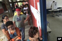 Electores brasileños esperan en fila en una estación de votación en un suburbio de Brasilia, el domingo 7 de octubre de 2018.