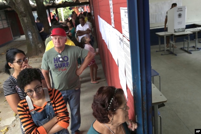 Electores brasileños esperan en fila en una estación de votación en un suburbio de Brasilia, el domingo 7 de octubre de 2018.