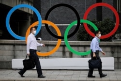 Men walk past the Olympic Rings in the commercial district of Nihonbashi during the Olympic games amid the coronavirus disease (COVID-19) outbreak in Tokyo, Japan August 4, 2021. REUTERS/Kevin Coombs