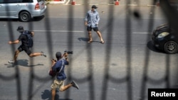 当缅甸防暴警察追上来时，仰光反军事政变的抗议者和一名记者跑开。（2021年2月27日）