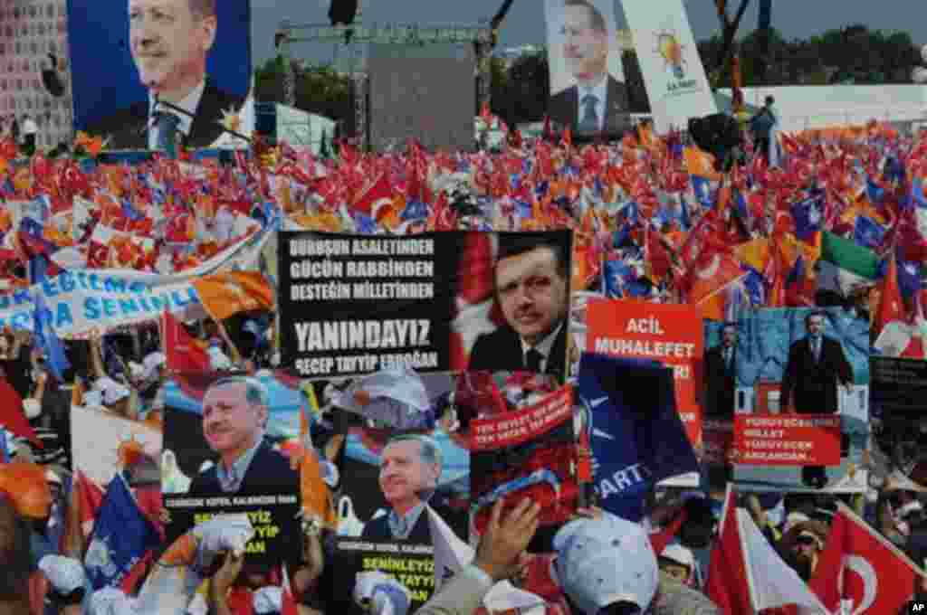 Supporters of Turkish Prime Minister Recep Tayyip Erdogan wave his posters before he arrives to address a party rally in Istanbul, Turkey, Sunday, June 16, 2013.The banner at the center reads: 'We are with you.' (AP Photo/Burhan Ozbilici) 