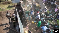 Kenyan school pupils and activists push down the wall leading to their playground, during a protest against the removal of their school's playground, at the Langata Road Primary School, in Nairobi, Kenya Monday, Jan. 19, 2015.