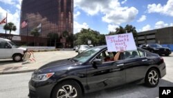 FILE - In this Tuesday, July 7, 2020 file photo, a teacher holds up a sign while driving by the Orange County Public Schools headquarters as educators protest in a car parade around the administration center in Orlando, Fla. (Joe Burbank/Orlando Sentinel via AP, File)