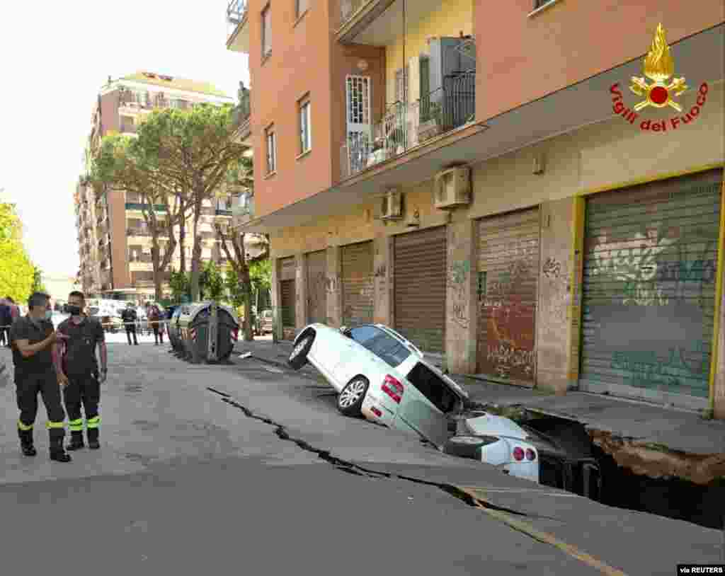 Cars are seen after falling into a large hole that opened up next to an apartment building in Rome, Italy. (Vigili Del Fuoco/Handout)