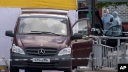 British forensic officers attend the scene of an apparent attack which has left one man confirmed dead and two people wounded near Woolwich barracks in London, May, 22, 2013.