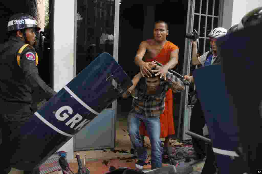 A Buddhist monk helps a worker who is being beaten by riot police inside a Buddhist pagoda in Phnom Penh, Cambodia, Nov. 12, 2013. 