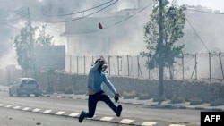 Un Palestinien lance une une pierre lors des affrontements contre les forces de sécurité israéliennes dans la ville de Bethléem, Cisjordanie, 31 mars 2018.