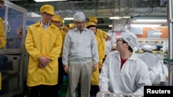 Tim Cook, izquierda, visita una línea de producción de iPhone en China. Un modelo de Mac será fabricado en Estados Unidos.