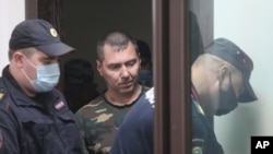 Alexander Popov, arrested on suspicion of murdering American student Catherine Serou, is escorted by police officers into a courtroom in the city of Gorodets, north-west of Nizhny Novgorod, Russia, June 20, 2021.