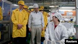 Apple Chief Executive Officer Tim Cook (L) visits the iPhone production line at the newly built Foxconn Zhengzhou Technology Park in Zhengzhou, Henan province, China, March 28, 2012 handout photo.