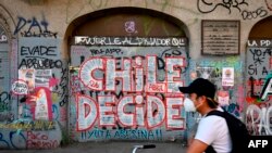 A man rides a bicycle past a wall with graffiti reading 'Chile decides' in Santiago, Chile, on Oct. 23, 2020, two days ahead of a referendum.