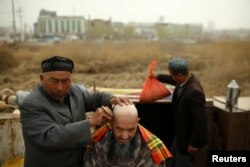 A street barber shaves the head of a man in Kashgar, Xinjiang Uighur Autonomous Region, China, March 24, 2017.