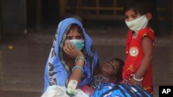 A woman along with her children wait for a train at Lokmanya Tilak Terminus in Mumbai, India, Wednesday, April 7, 2021.