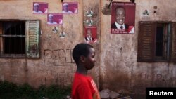 A child walks past posters for political candidates plastered on a house in Bamako, July 22, 2013.