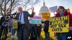 Sen. Bernie Sanders, I-Vt., joins protesters outside the Capitol as Republicans in the Senate work to pass their sweeping tax bill.