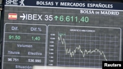 A clock stands in front of electronic boards at the Madrid stock exchange, June 19, 2012. 