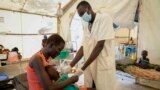 FILE: A woman's malnourished child is attended by a doctor in a hospital in Jonglei state, South Sudan Tuesday, Dec. 28, 2021. Aid groups say more will face hunger this year, because of severe floods as well as conflict and the sluggish implementation of the peace agreement.