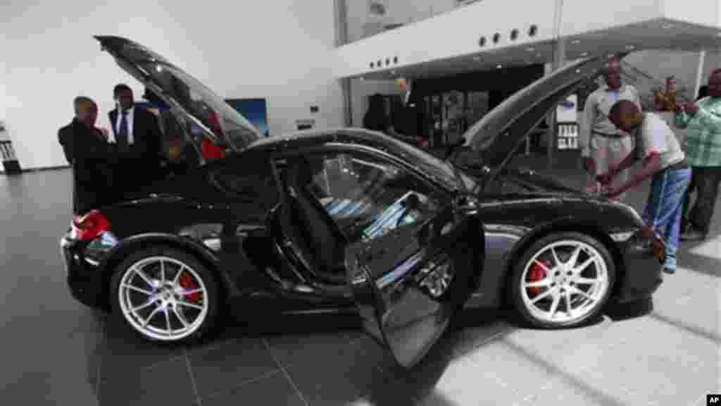 Wani dan jarida a Najeriya na duba wata sabuwar mota kirar Porsche Cayman S a cikin wani gidan tallar motoci a tsuburin Victoriya dake jihar Ikko a Najeriya. Alhamis, Mayu 9, 2013.