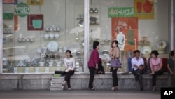 지난 2016년 북한 평양 시내의 백화점 쇼윈도 앞에 시민들이 앉아있다. 쇼윈도 안에는 주방용품과 식기가 전시돼있다.