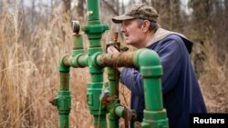 Hanson Rowe, a landowner who blames a leaky gas well on his property for health problems, smells for the odor of gas emanating from an abandoned well on his property in Salyersville, Kentucky, U.S., February 28, 2020. (REUTERS/Bryan Woolston)