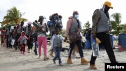 Migrantes, en su mayoría haitianos, caminan para abordar botes que los llevarán a Acandi, para cruzar a Panamá para continuar su viaje hacia Estados Unidos, en Necoclí, Colombia, el 23 de septiembre de 2021. 