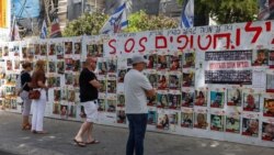 Warga Israel berdiri di depan tembok di Tel Avivdengan poster mendukung para sandera yang diculik kelompok Islam Palestina Hamas, di tengah konflik di Gaza antara Israel dan Hamas, 23 April 2024. 