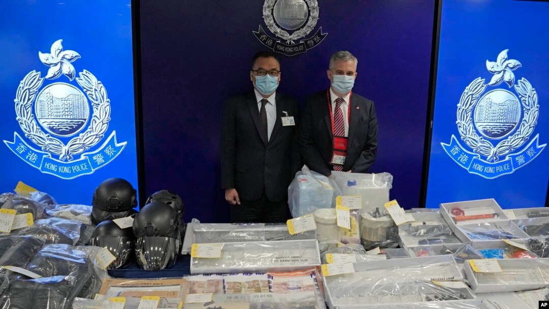 Inspektur Senior Li Kwai-wah (kiri, Departemen Keamanan Nasional Kepolisian Hong Kong), dan petugas penjinak bom senior Alick McWhirter (Biro Pembuangan Senjata Peledak), bersama barang bukti yang disita selama konferensi pers di Hong Kong, 6 Juli 2021. (AP Photo/Kin Cheung)