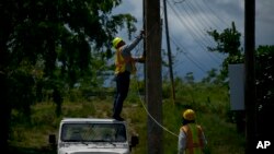 Workers of the electric repair brigade remove old cables from a post in San German, Puerto Rico, May 30, 2018. 