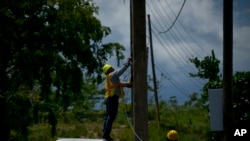 Para mekanik listrik membuang kabel-kabel tua dari tiang listrik di San German, Puerto Rico, 30 Mei 2018. 